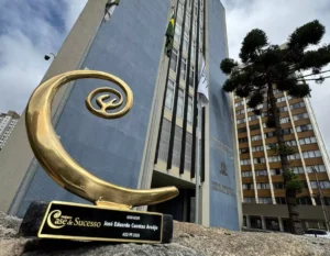 Projeto do Sistema Fiep que utiliza inteligência artificial para personalizar a preparação de estudantes para o Exame Nacional do Ensino Médio (Enem) foi reconhecida como o case de inovação do Paraná pela comunidade 4CIO, rede nacional que reúne executivos de tecnologia de diferentes setores para compartilhar experiências e soluções de transformação digital. A iniciativa reforça o compromisso do Sistema Fiep em utilizar tecnologia e inovação para ampliar oportunidades educacionais e apoiar a formação de estudantes preparados para os desafios do futuro. A proposta surgiu a partir da identificação de um desafio comum na preparação para o Enem: o modelo tradicional de ensino costuma seguir uma lógica padronizada, que nem sempre considera as diferenças de ritmo, compreensão e dificuldades específicas de cada aluno. A partir dessa constatação, foi estruturado um projeto para aplicar inteligência artificial na jornada de aprendizagem, tornando o processo de estudo mais personalizado, adaptativo e orientado por dados. Tecnologia a serviço da aprendizagem Na prática, a tecnologia atua em diferentes etapas da preparação dos estudantes. O processo começa com um diagnóstico inicial estruturado com base em princípios de neurociência educacional, capaz de identificar lacunas de conhecimento e padrões de dificuldade de cada aluno. Com base nessas informações, a plataforma gera automaticamente um plano de estudos personalizado. À medida que o estudante interage com o sistema, a inteligência artificial passa a analisar continuamente seu desempenho, identificando padrões de erro, evolução por área de conhecimento e nível de engajamento. Esses dados permitem que o próprio sistema ajuste o conteúdo apresentado, sugira novos exercícios e direcione o foco de estudo para os pontos que realmente precisam de reforço. O resultado é uma jornada de aprendizagem adaptativa, em que cada estudante passa a contar com um plano de preparação único, alinhado ao seu ritmo e às suas necessidades. Segundo José Eduardo Cuestas Araujo, gerente de Tecnologia da Informação do Sistema Fiep, o objetivo da iniciativa é usar a tecnologia como aliada para ampliar o potencial de aprendizagem dos estudantes. “A proposta foi utilizar inteligência artificial para compreender melhor as dificuldades de cada estudante e apoiar o desenvolvimento de uma preparação mais eficiente para o Enem. Com isso, conseguimos estruturar uma jornada de aprendizagem mais personalizada e orientada por dados”, afirma. Reconhecimento em comunidade nacional de tecnologia O case foi apresentado durante encontro da comunidade 4CIO no Paraná, que reúne lideranças de tecnologia para debater iniciativas de inovação e transformação digital em diferentes segmentos. Na ocasião, o Sistema Fiep concorreu com projetos apresentados por organizações como a cooperativa Cocamar Cooperativa Agroindustrial, o Hospital Marcelino Champagnat, a BBM Logística, o Hospital Erasto Gaertner e a J. Malucelli. Após as apresentações, os executivos de tecnologia presentes realizaram uma votação por meio do aplicativo oficial da comunidade, elegendo a iniciativa do Sistema Fiep como o projeto mais relevante e inovador da etapa estadual. Para Cuestas, o reconhecimento reforça a relevância da inovação aplicada à educação: “esse reconhecimento mostra como a tecnologia pode contribuir para transformar a experiência de aprendizagem. É uma iniciativa que nasce no campo educacional, mas dialoga diretamente com o futuro da inovação e da formação de talentos”. Rumo à etapa nacional Com o resultado, o Sistema Fiep foi convidado a apresentar o projeto na etapa nacional da premiação, que será realizada no final do ano em São Paulo. O encontro reunirá cases vencedores de diferentes estados e executivos de tecnologia de setores como indústria, saúde, logística, serviços e governo. Paralelamente, a iniciativa seguirá em evolução dentro do ecossistema educacional do Sesi. A plataforma continuará sendo aprimorada com base nos dados gerados pela interação dos estudantes, permitindo aprofundar estratégias de aprendizagem adaptativa e ampliar o uso da inteligência artificial na educação. Embora os resultados acadêmicos finais ainda estejam em processo de mensuração, os primeiros indicadores já apontam forte engajamento dos estudantes com a ferramenta. Os diagnósticos iniciais e os planos de estudo personalizados já estão sendo utilizados como apoio à preparação para o Enem, gerando informações importantes sobre padrões de aprendizagem e comportamento de estudo. Projeto do Sistema Fiep que usa inteligência artificial na preparação para o Enem é reconhecido como case de inovação no Paraná