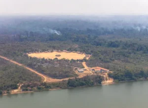 Aldeia Metuktire, à beira do Rio Xingu, onde vive o cacique Raoni, cercada por ar esfumaçado e paredões de fumaça, que mostram fogo ativo. Crédito: Marizilda Cruppe/Greenpeace Brasil